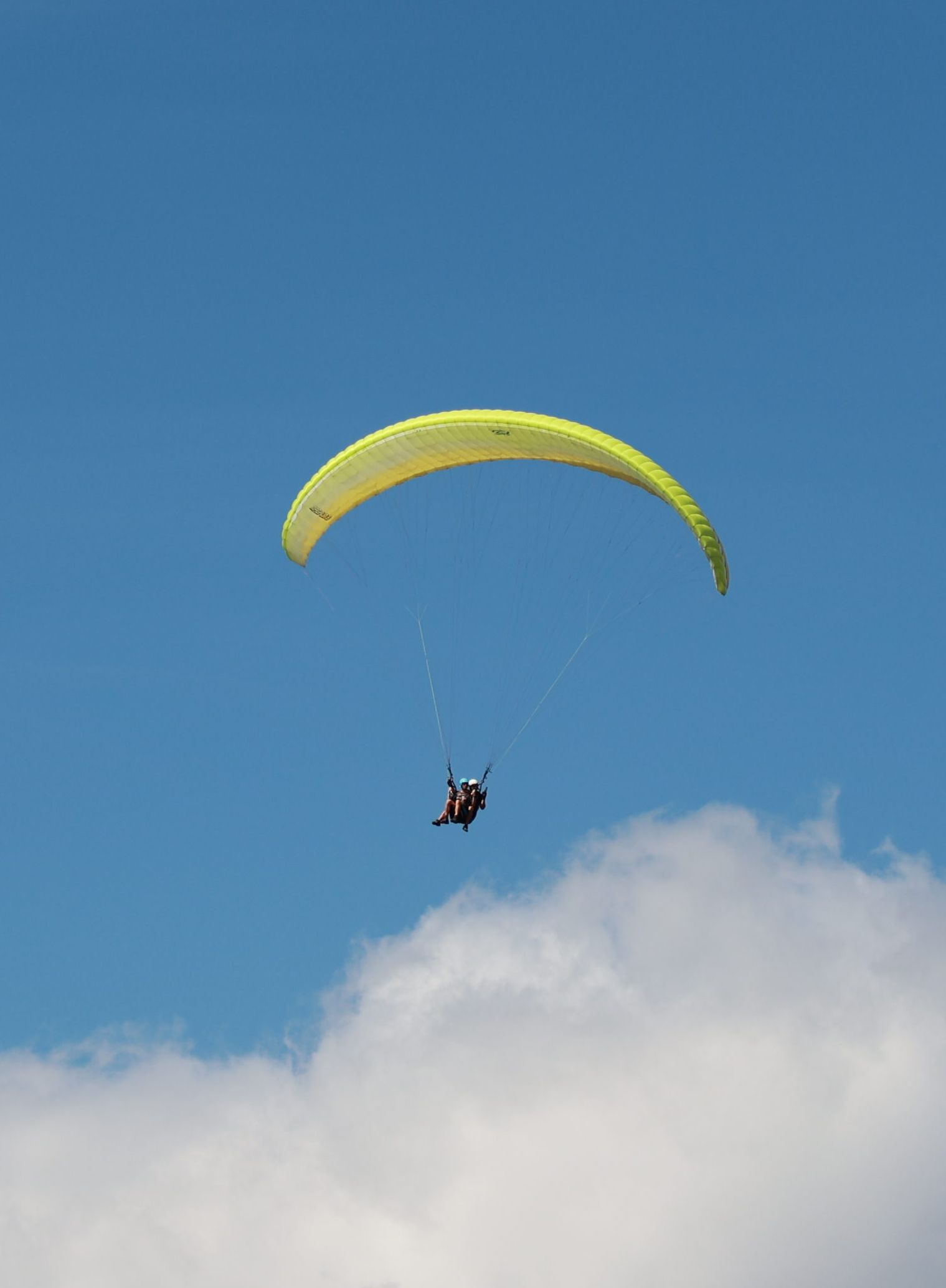 Tandem-Gleitschirm am blauen Himmel über den Wolken