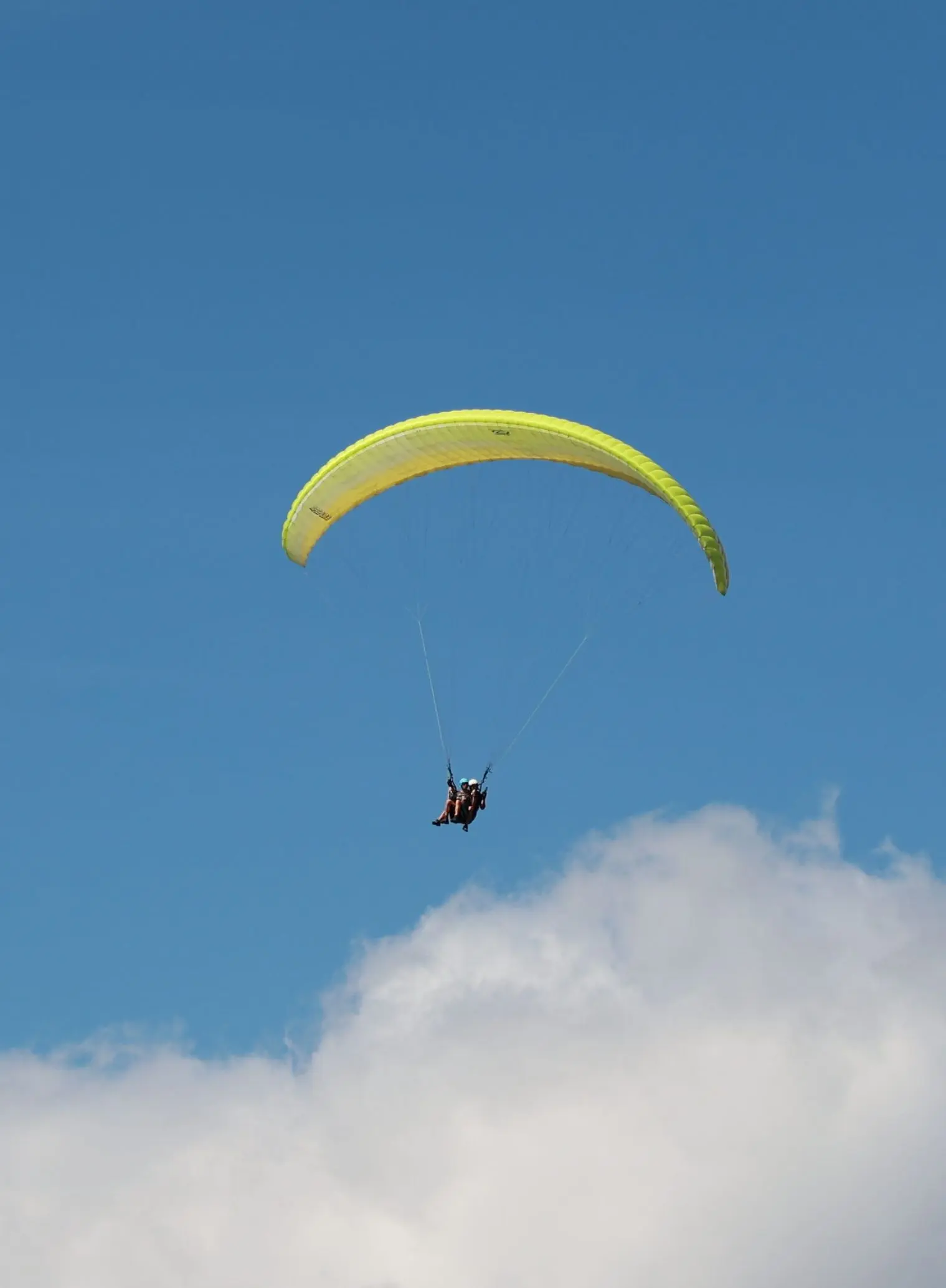 Tandem-Gleitschirm am blauen Himmel über den Wolken