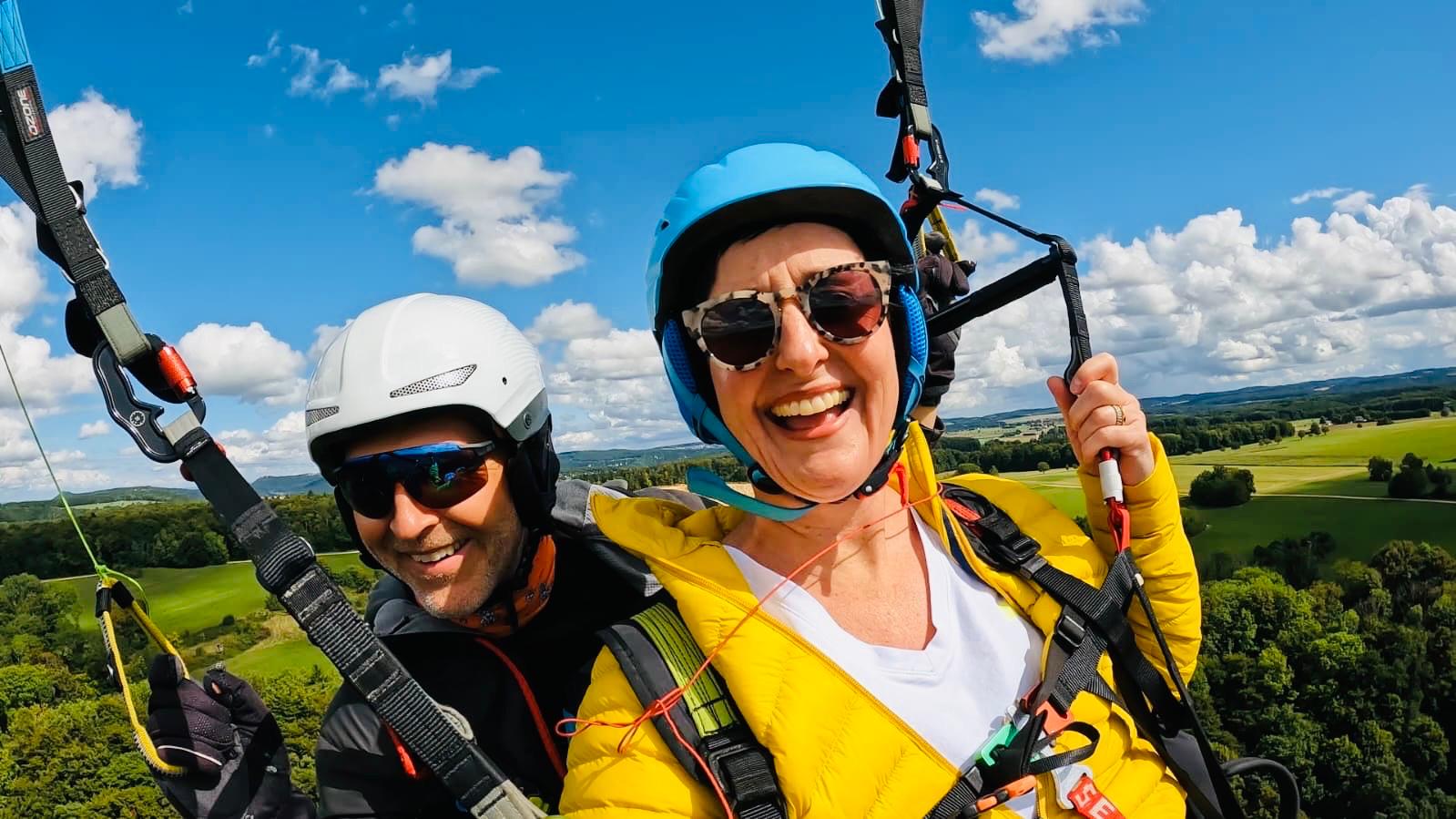 Gleitschirm-Tandemflug: Pilot Gunnar mit begeisterter Passagierin hoch über der Landschaft
